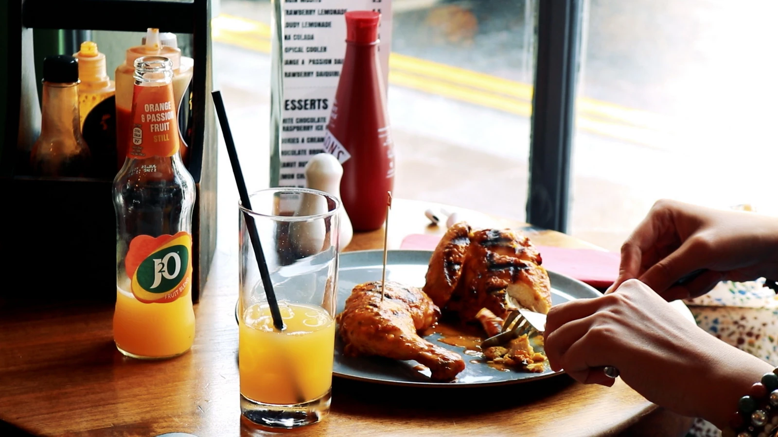 Flame-grilled half chicken being tucked into at a window table